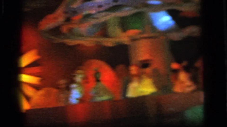 Soft 8mm frame of colorful amusement scenery with a red circular element, small figure shapes, and a blue light flare.