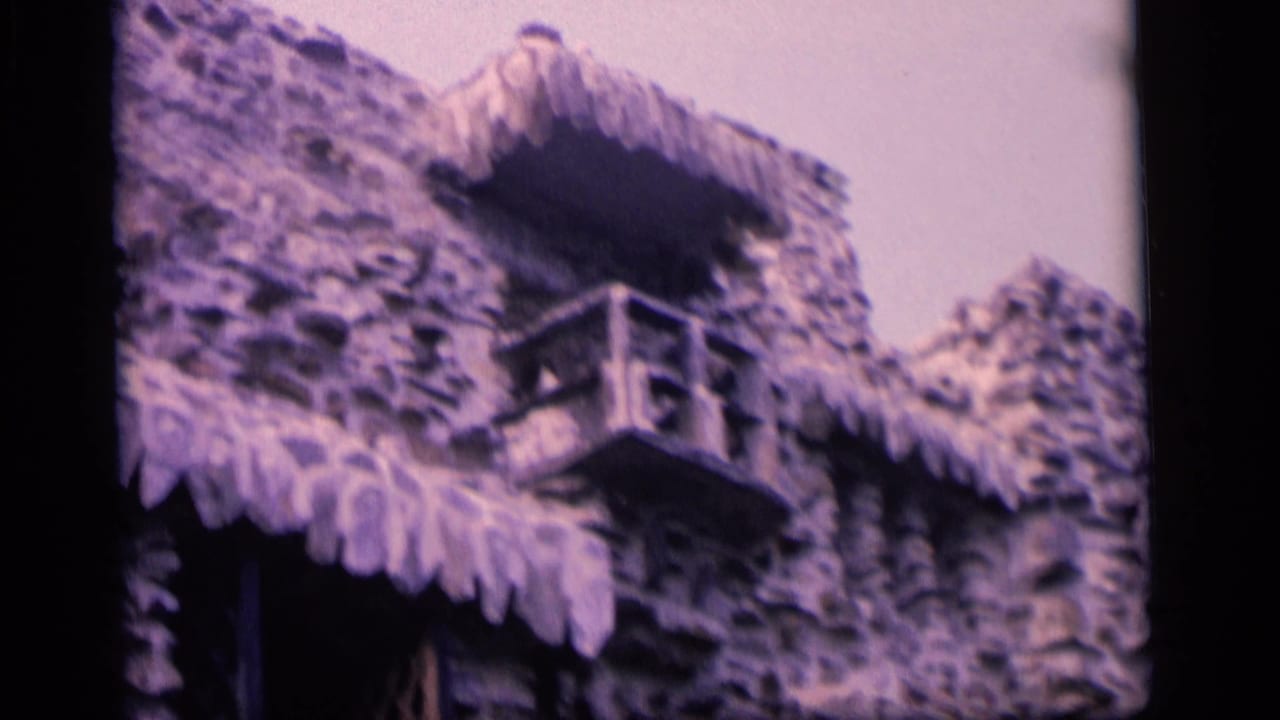 Upper stone wall with small balcony and scalloped roofline.