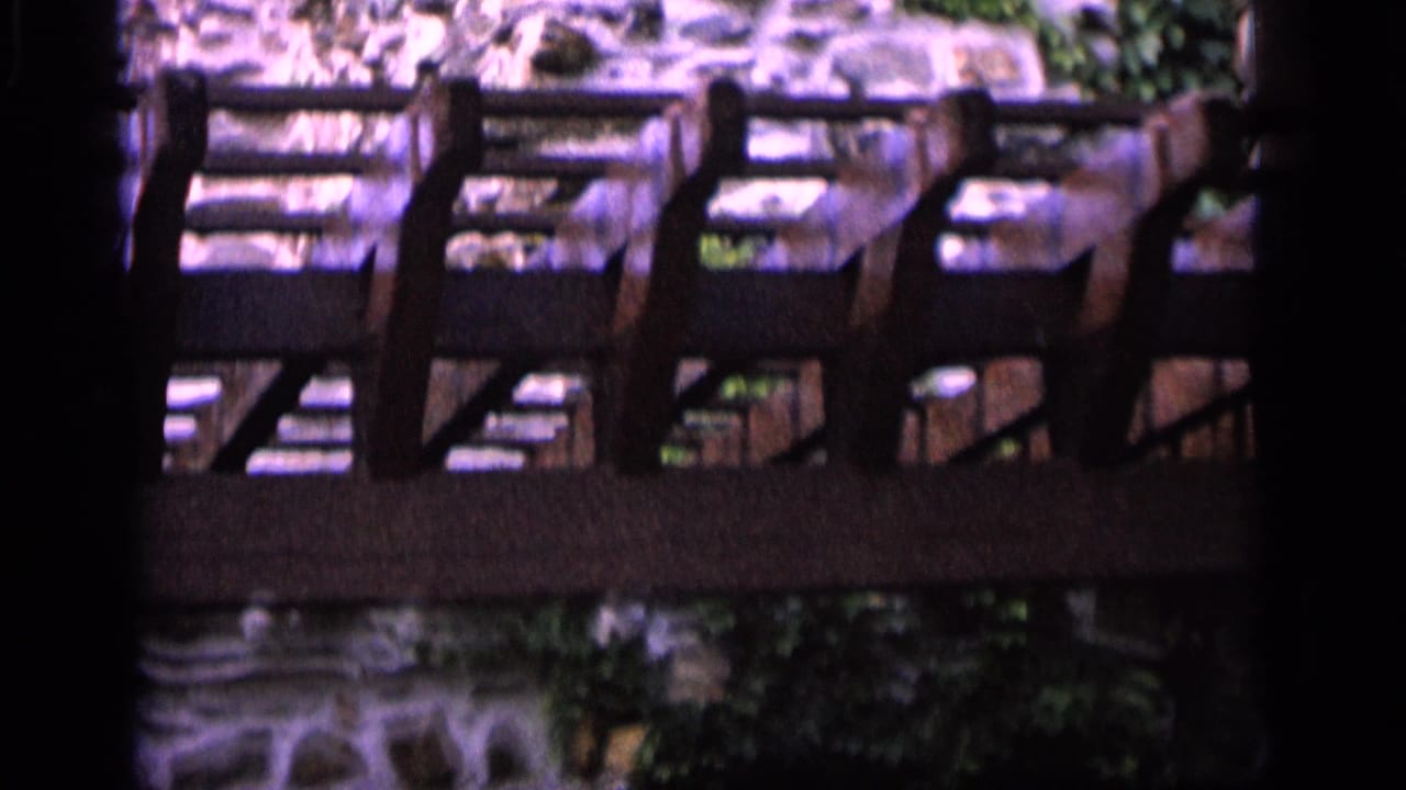 Wooden railing crossing a stone wall with ivy and shadowed edges.