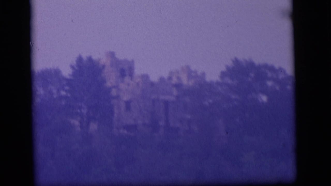 1964 Camden home-movie frame with a ruined building partially obscured by foliage and heavy purple 8mm color shift.