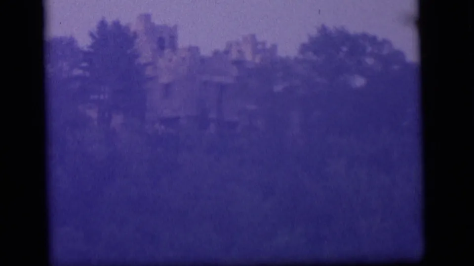 Final 1964 Camden frame showing the secluded ruined structure at a distance, softened by grain, haze, and dense vegetation.