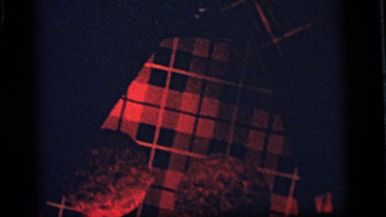 Red plaid object fills the upper frame with dark shadows around it.