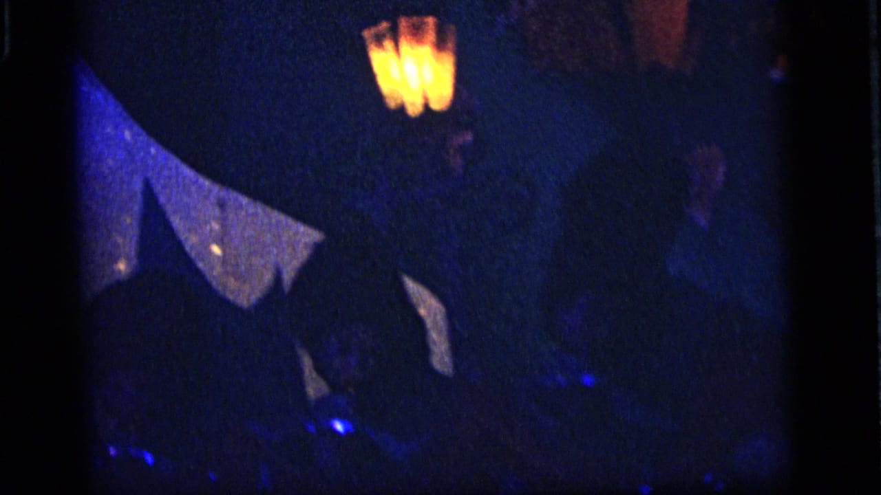 1964 Camden, New Jersey 8mm frame showing a dim ride interior with blue-lit forms and a glowing lantern above shadowed scenery.