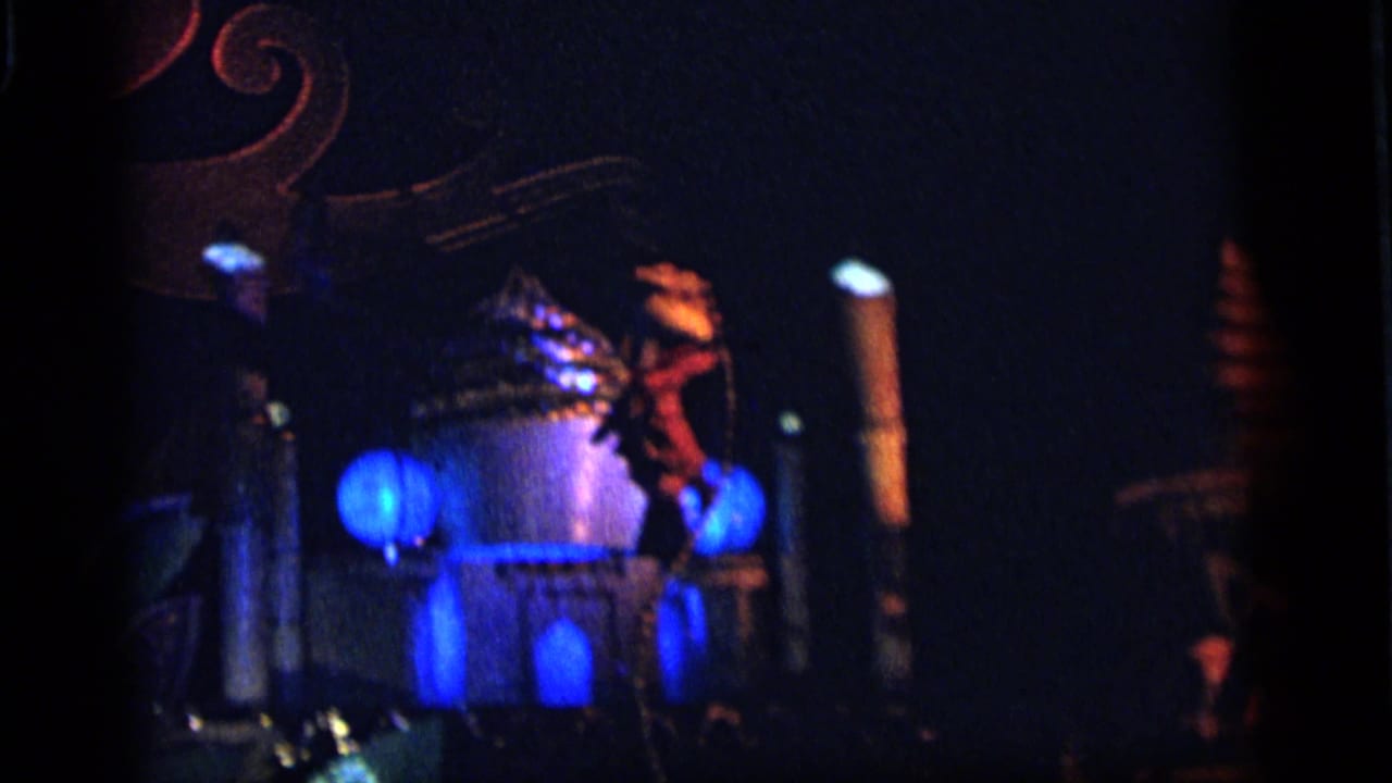 Blue-lit structure with glowing globes and a costumed figure at night.