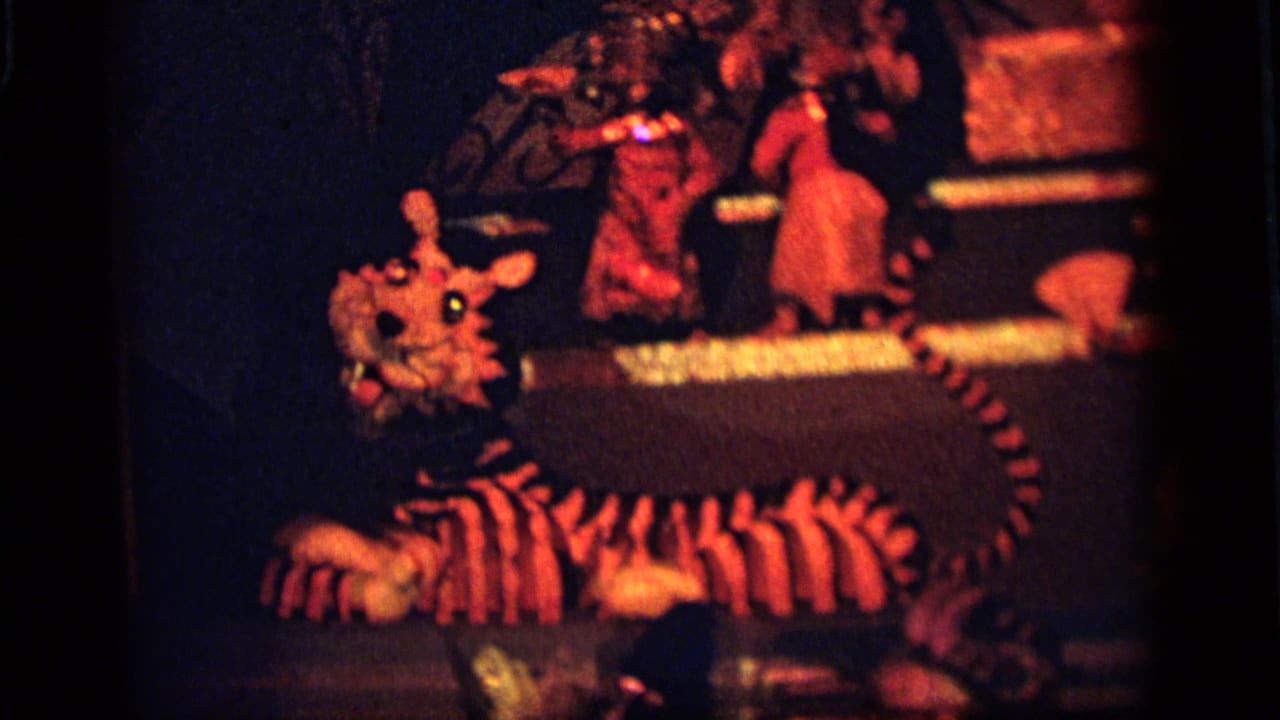 Striped tiger figure on a small stage with other animal-like figures behind it.