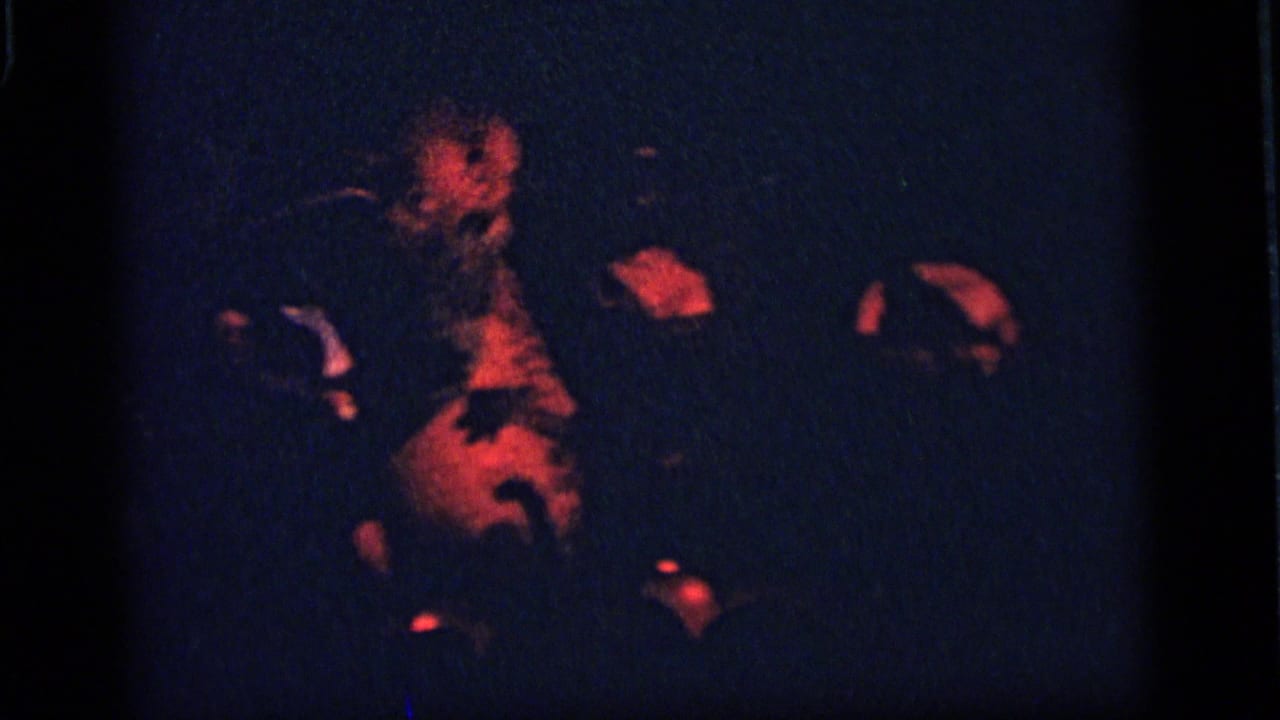 1964 Camden home-movie frame with a red-lit animatronic animal figure in a darkened display under blue shadow and visible grain.