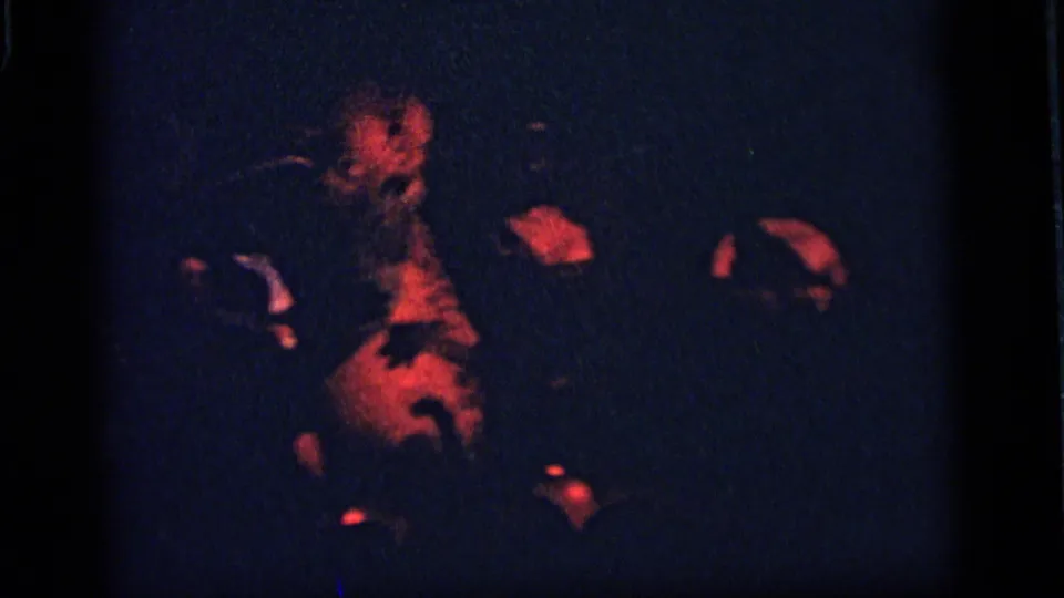 1964 Camden home-movie frame with a red-lit animatronic animal figure in a darkened display under blue shadow and visible grain.