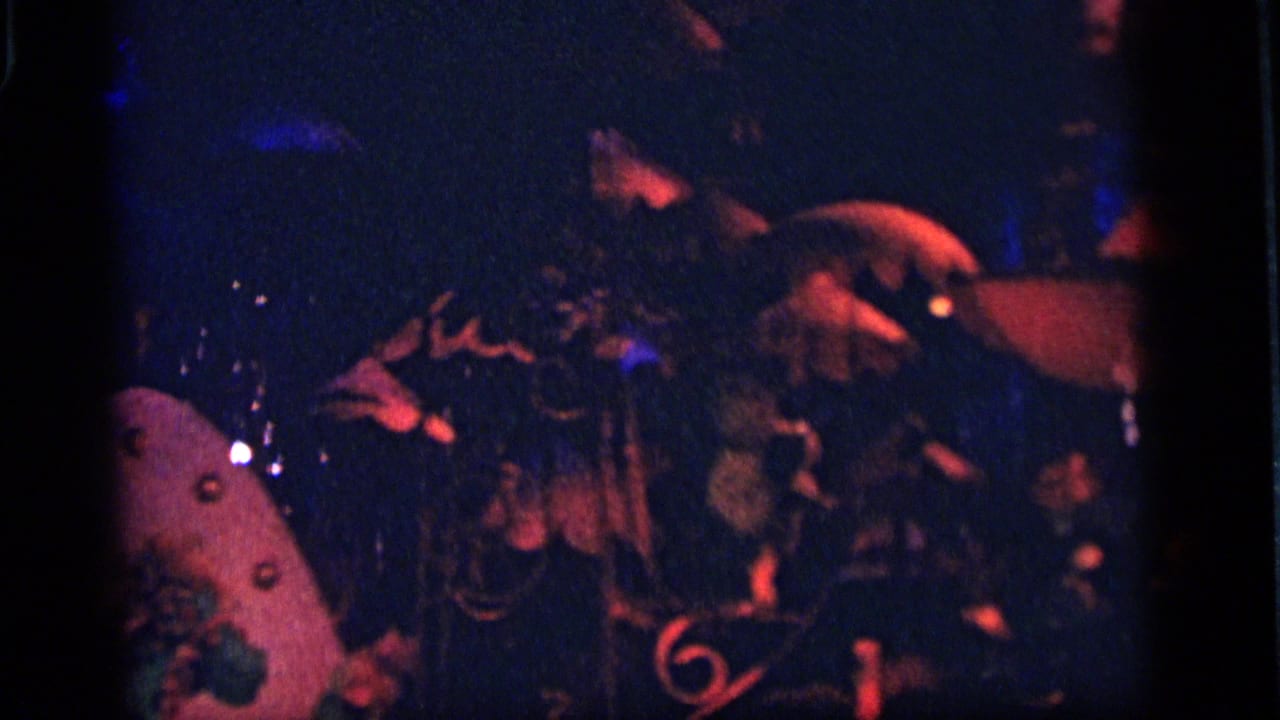 1964 Camden frame showing a grainy nighttime amusement display with mechanical-looking forms, ornament, and colored light.