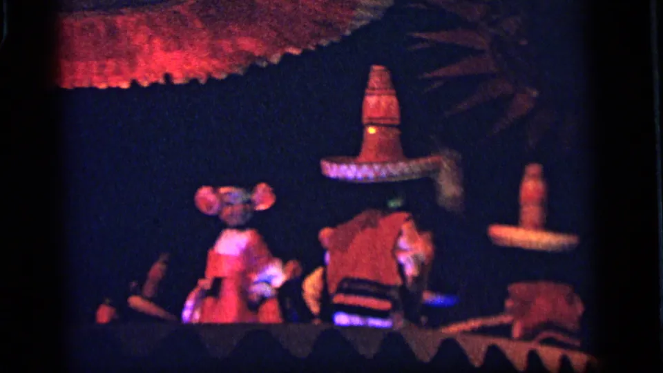 1964 Camden frame with blue and red lighting over umbrella-like canopies and small festival figures on a dark set.