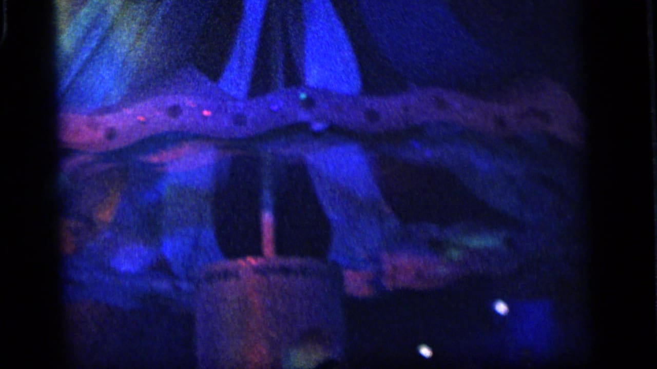 1964 Camden frame showing a blue-lit umbrella or tree-like decorative structure with small lights and dark surrounding space.