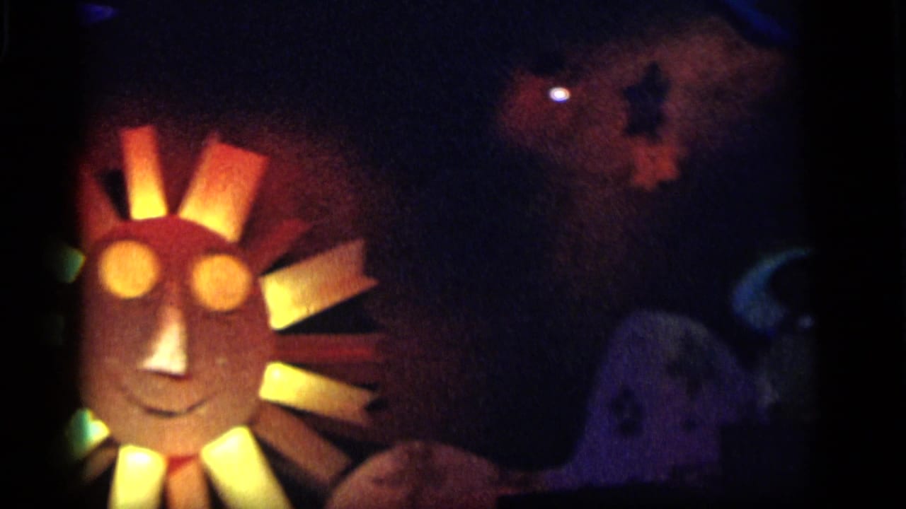 1964 Camden nighttime carnival frame with a glowing sun face, warm ray panels, and shadowed blue-lit display shapes nearby.