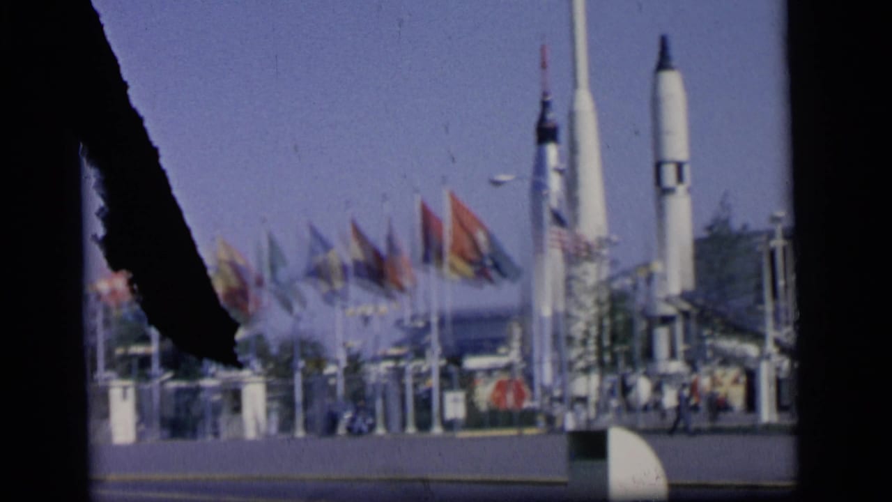 National flags and rocket displays seen through a dark damaged film edge.