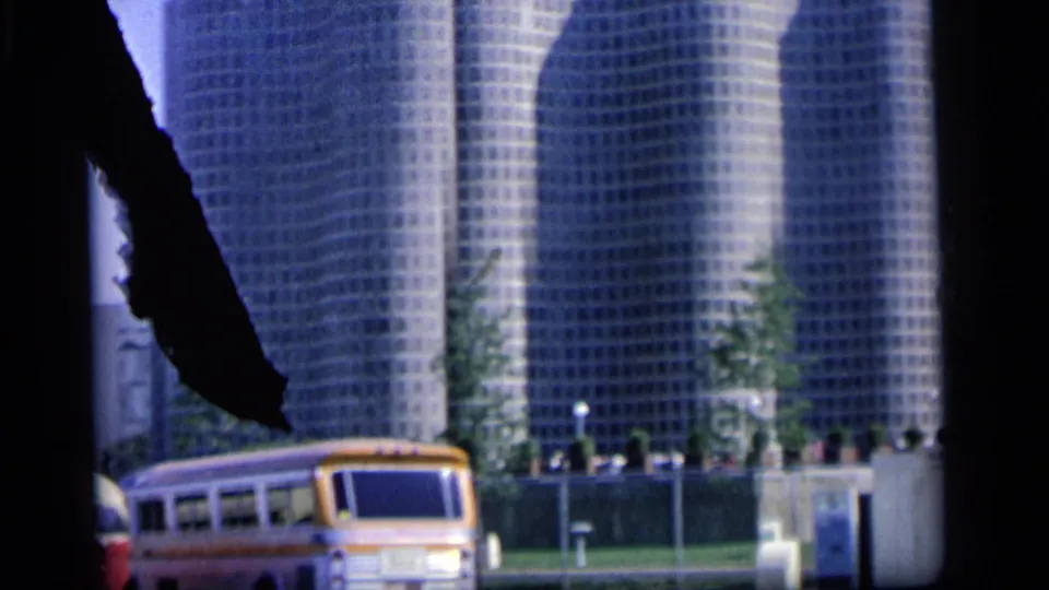 1964 Camden street view with modern grid-faced towers and a yellow and white bus passing in the foreground.