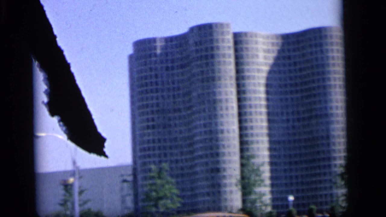 Modern office towers in Camden, New Jersey, seen from a partially obstructed 8mm home-movie viewpoint.