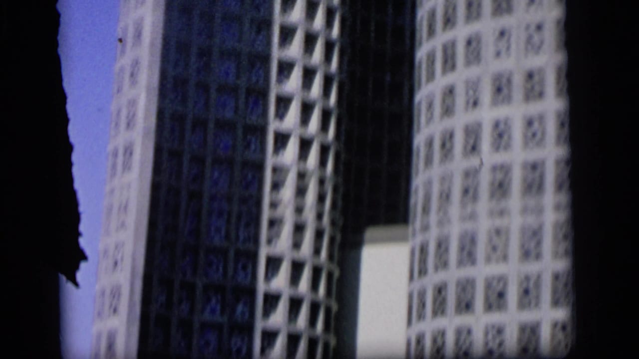 Close view of tall patterned white building surfaces separated by a dark frame edge.