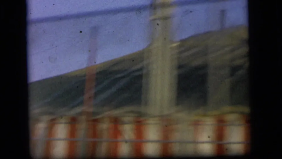 Moving-vehicle view of a blurred tent side with red-and-white striped trim and vertical poles in Camden, New Jersey, 1964.