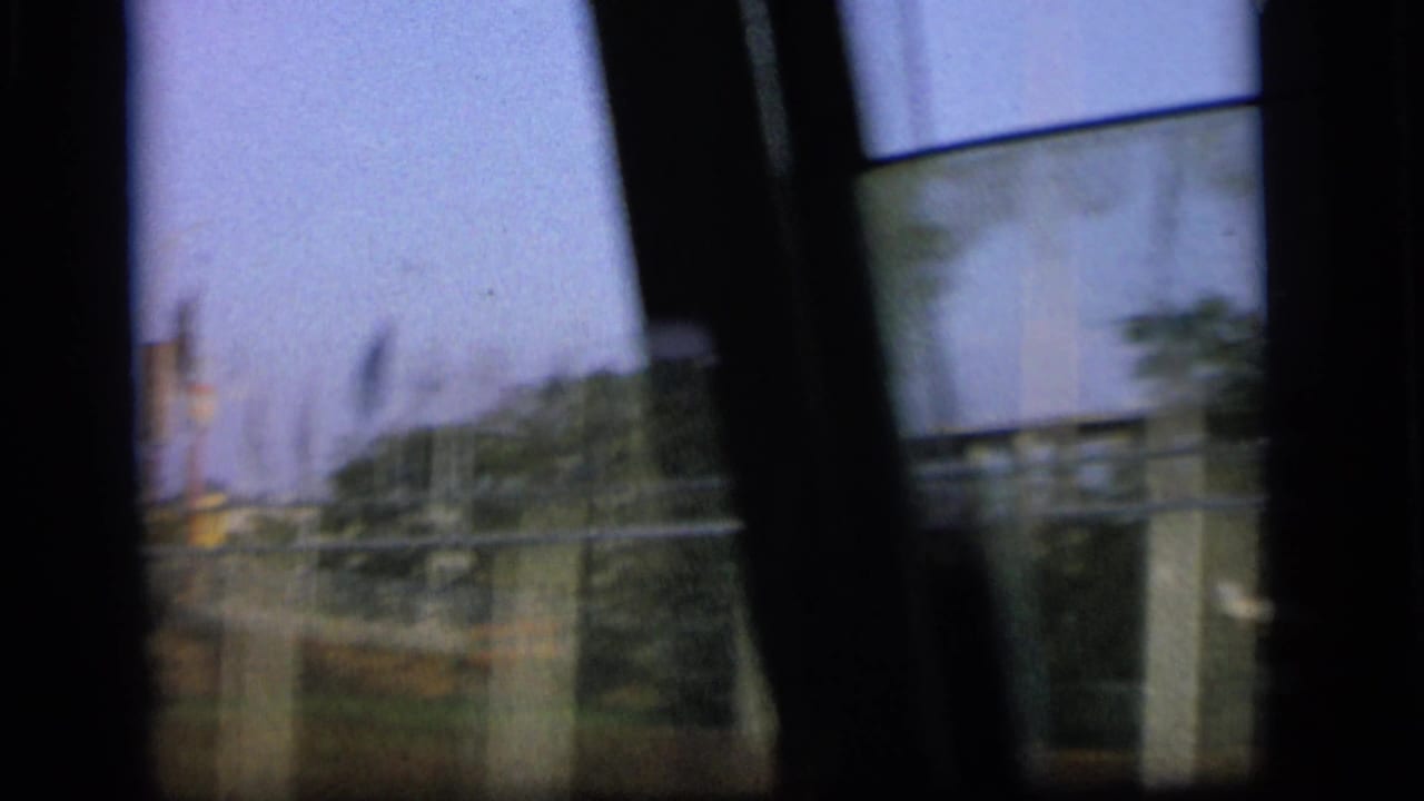 Blurred view through a vehicle window with roadside structures and dark interior framing.