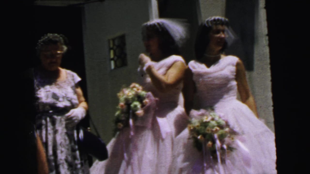 1964 Camden wedding footage shows the bridal party waiting outside, with an older woman and brickwork visible nearby.