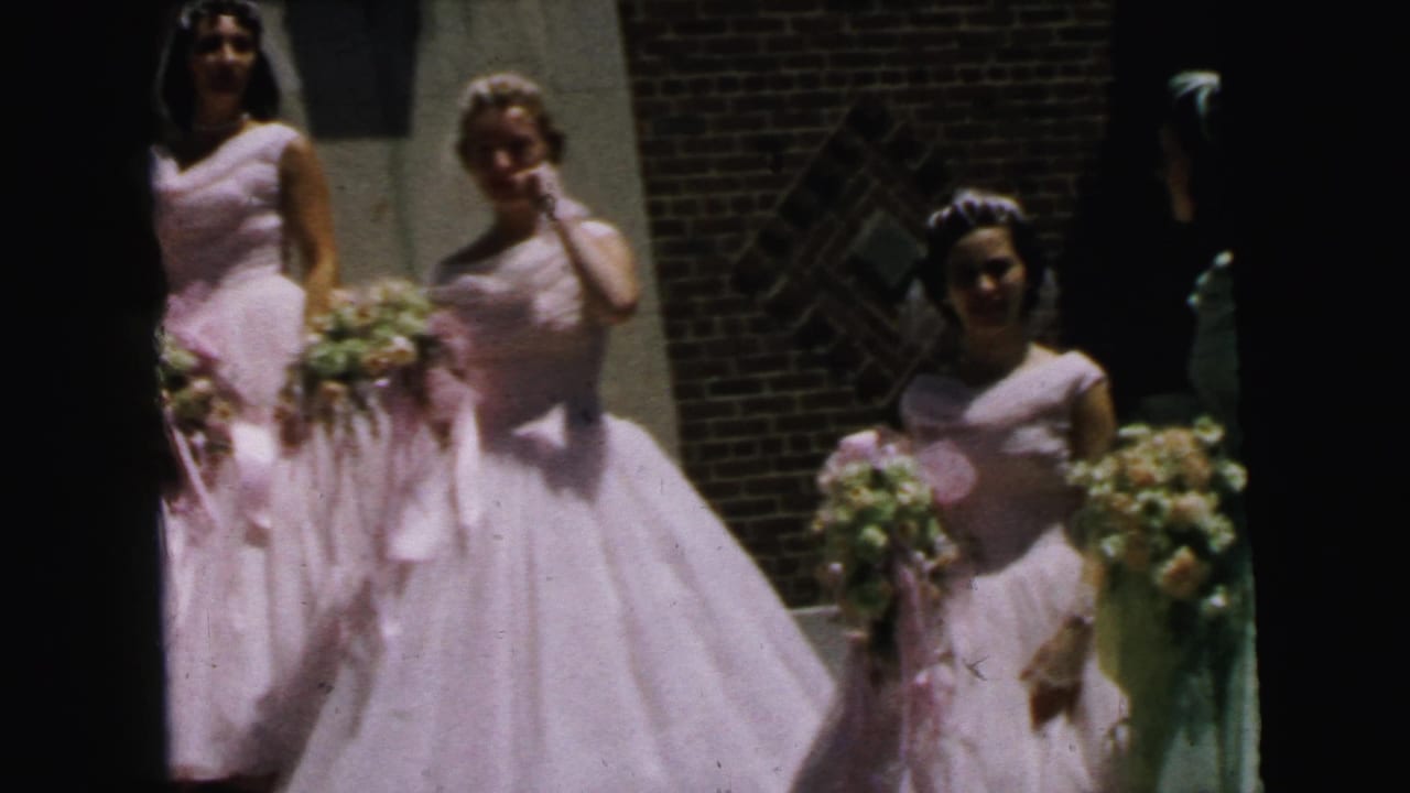 1964 Camden frame with three bridesmaids in formal pale dresses, veils, and flower bouquets positioned near a brick doorway.
