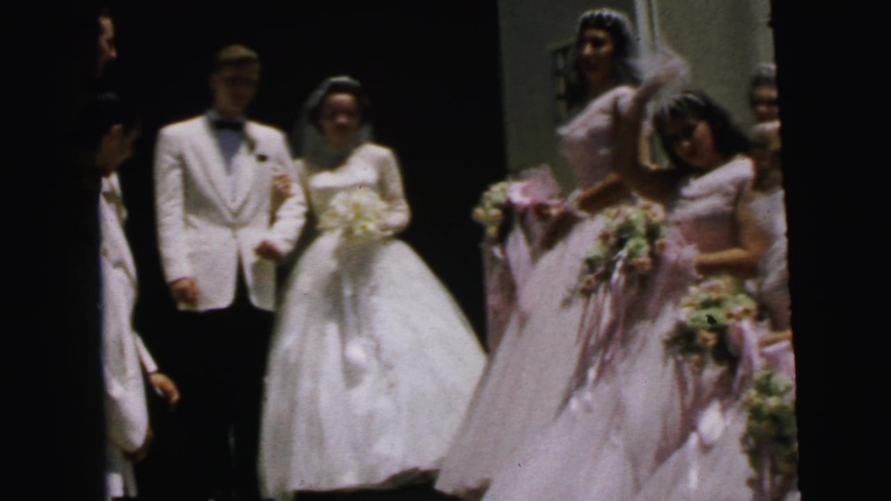1964 Camden, New Jersey wedding party with bride, groom, and pink-dressed bridesmaids near an entrance.