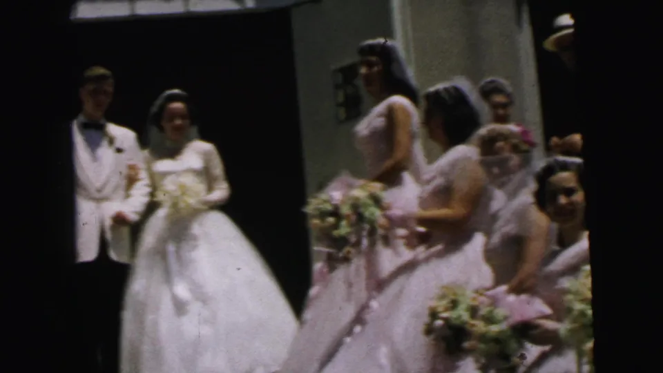 1964 Camden wedding scene with the couple walking near bridesmaids in pink dresses and floral bouquets.