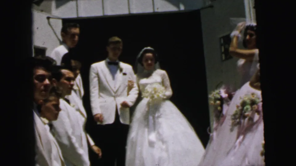 The bride and groom pose outside the Camden church, surrounded by groomsmen, guests, and bridesmaids in pale dresses with bouquets.