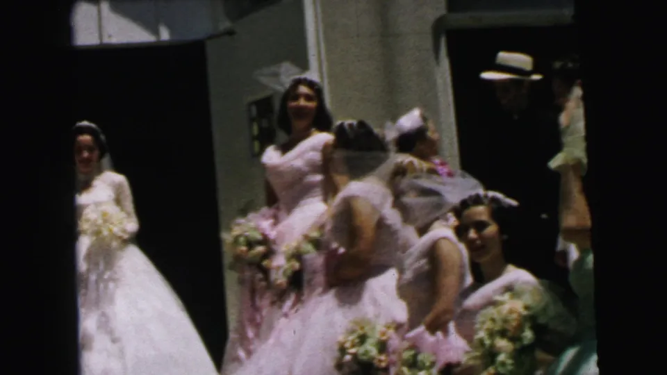 The bride and pink bridesmaids move on the church steps in Camden, with bouquets and veils visible as a man in a straw hat stands in the doorway.