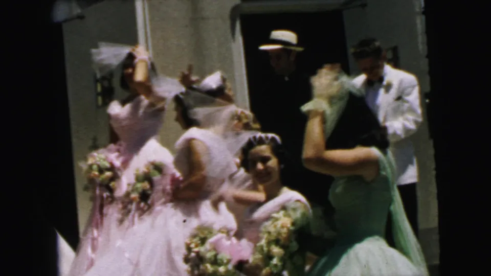 At the Camden wedding exit, the groom and attendants stand near bridesmaids in pink dresses, with bouquets, veils, and the church entrance behind them.