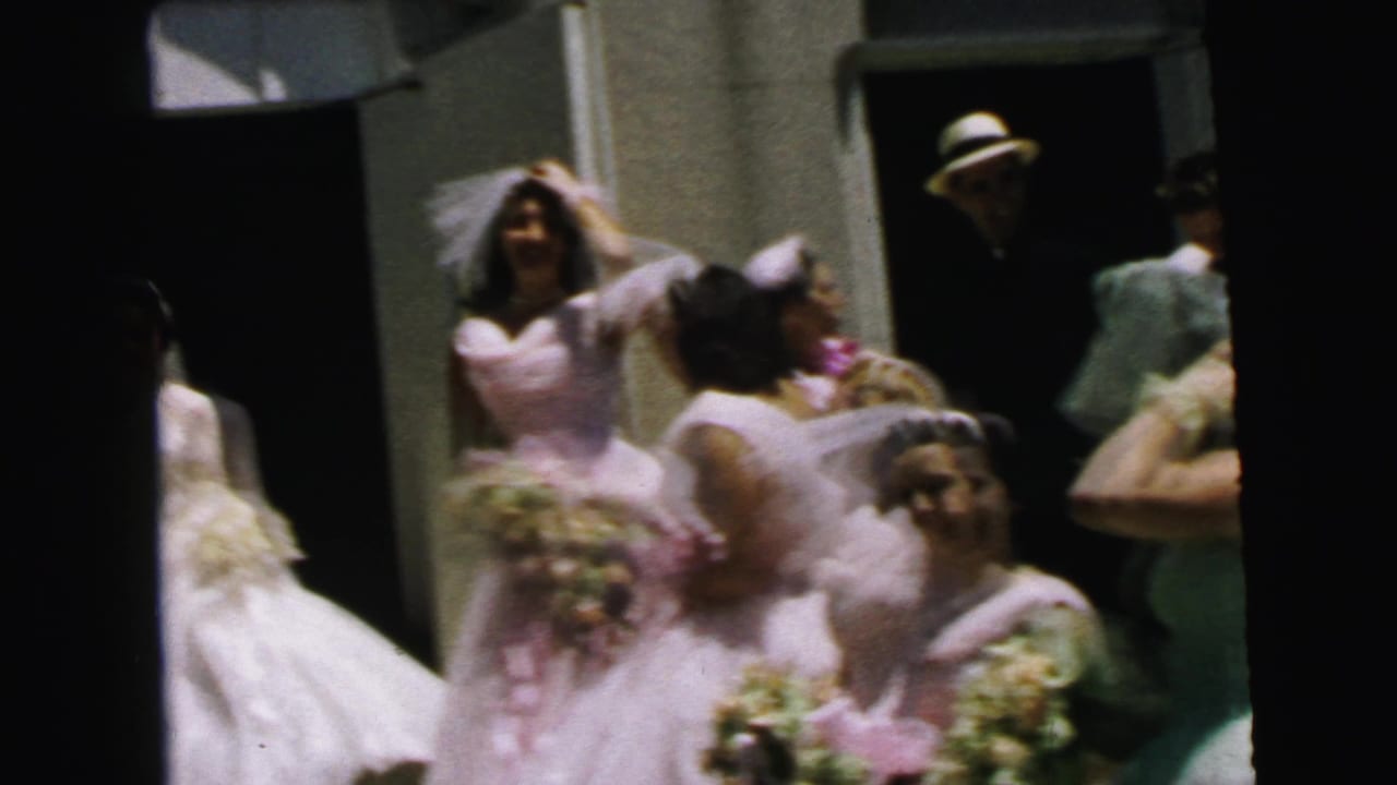 Bride, groom, and bridesmaids gather near a doorway during a wedding exit.