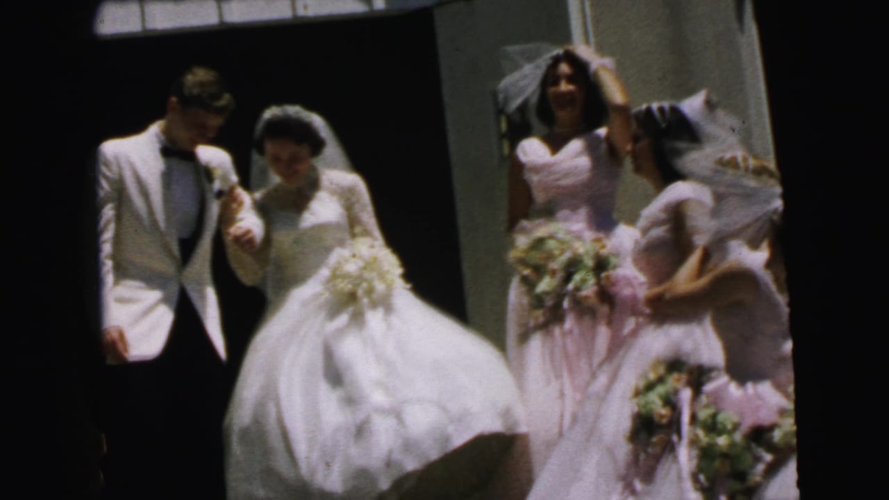 Bride and groom walk arm-in-arm beside bridesmaids holding bouquets.