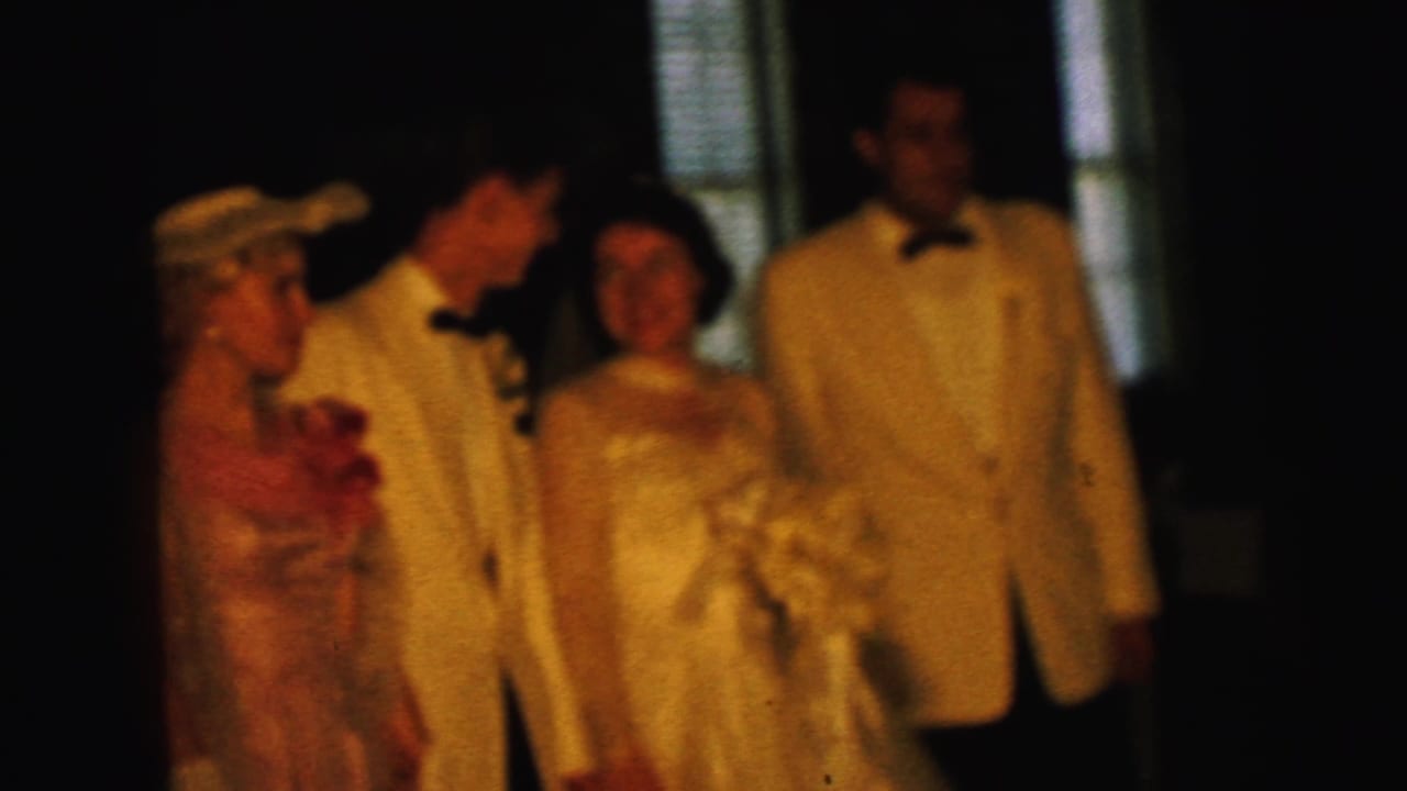 1964 Camden wedding party appears indoors, with bride holding bouquet beside groom, bridesmaid, and another man in white tuxedo.
