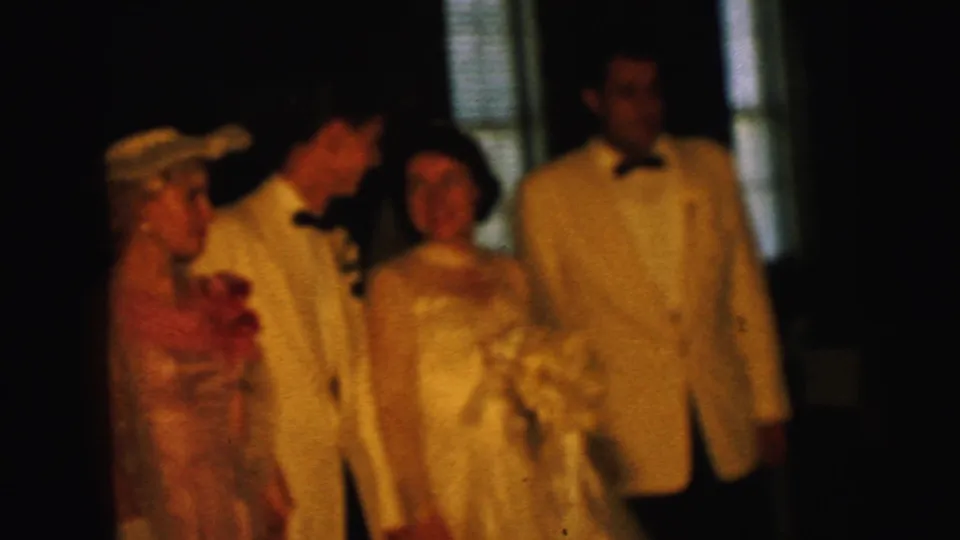 1964 Camden wedding party appears indoors, with bride holding bouquet beside groom, bridesmaid, and another man in white tuxedo.