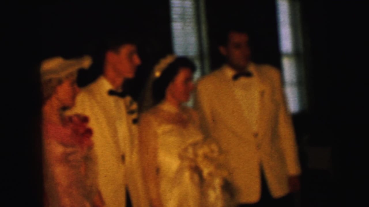 Bride and groom with attendants standing indoors in dim warm light.