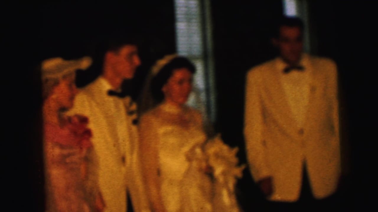 Wedding party remains posed, with bride holding flowers beside groom and attendants.