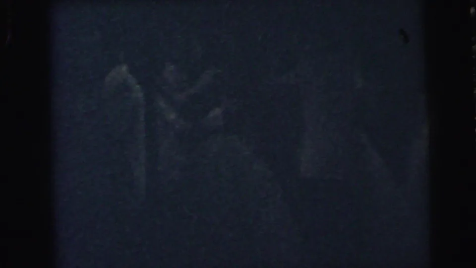 Grainy Camden 1964 home-movie frame with barely visible couples continuing to dance in low evening light.