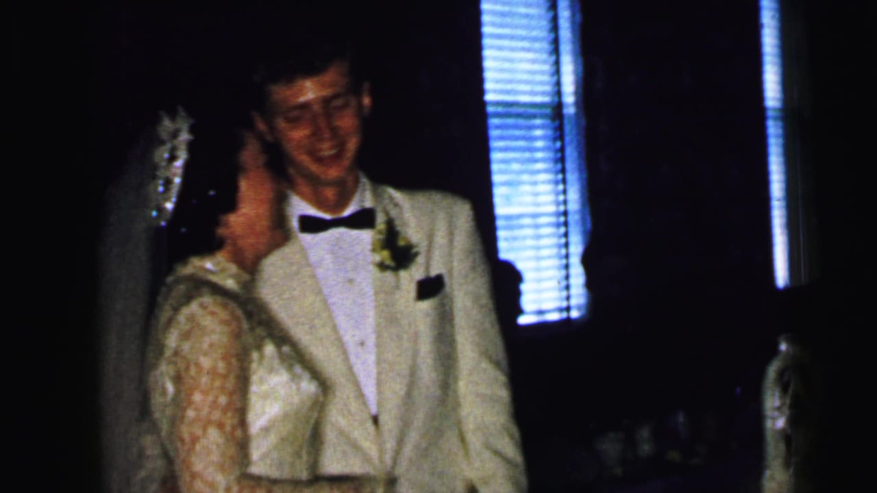 Bride and groom standing close during a dimly lit wedding reception.