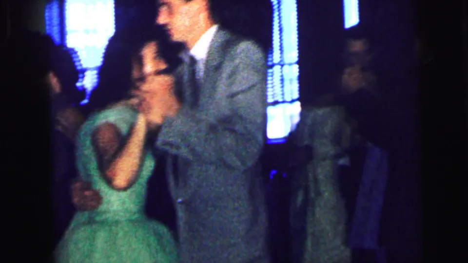 A guest couple dances in the Camden wedding reception footage, with seated people and blue-lit windows behind them.
