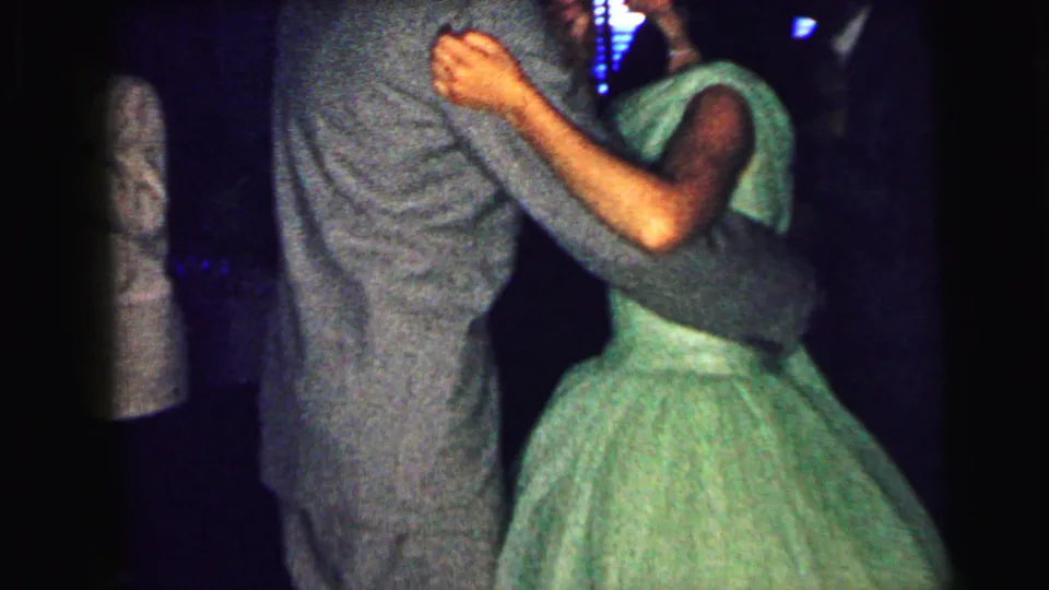1964 Camden 8mm frame showing the green-dressed dancer close to her partner, with the camera cropped tight on the moving pair.