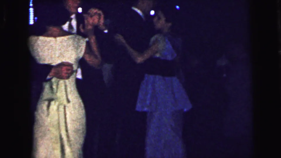 1964 Camden dance scene with a woman in a white dress and other couples moving in low light.