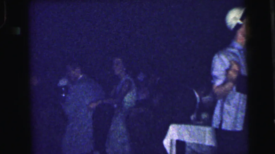 1964 Camden homecoming dance frame showing couples in low light near a white-clothed table at the edge of the floor.