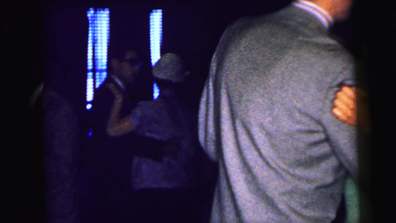 Couple dancing in a dark room with blue vertical lights behind them.