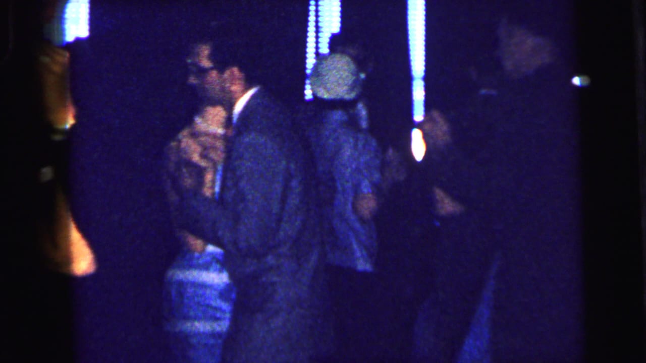 Several adults dancing under blue lights in a dark club-like room.
