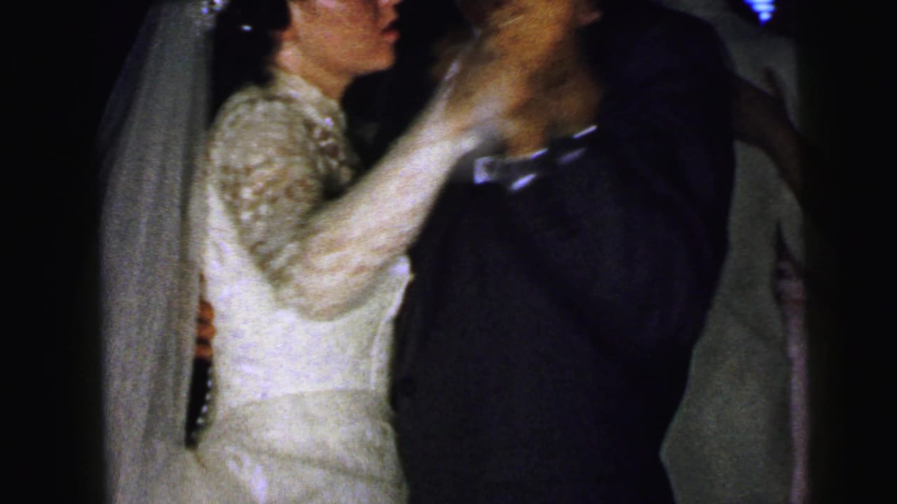 Bride in profile dances with the groom, her veil and lace sleeve visible.