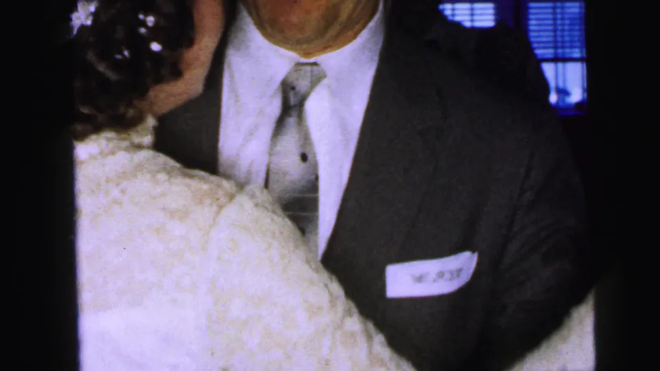 The bride faces a suited groom with a visible paper name tag as they dance at a 1964 Camden wedding reception.