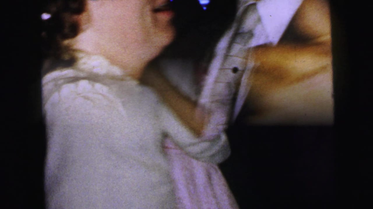 At a 1964 Camden formal gathering, a woman in a white dress dances closely with a man in a light suit, partly cropped by the 8mm framing.