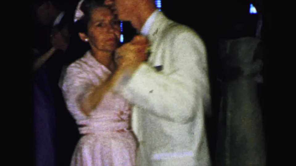 At a 1964 Camden, New Jersey wedding reception, a woman in a pale dress dances closely with a man in a light suit.