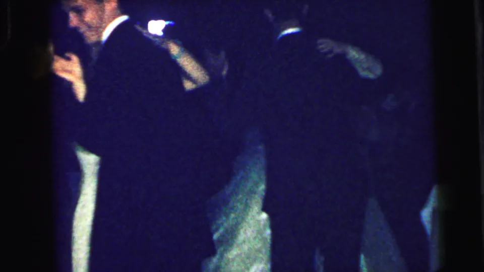 Low-light 8mm footage from the 1964 Camden wedding reception shows shadowed guests moving on the dance floor.