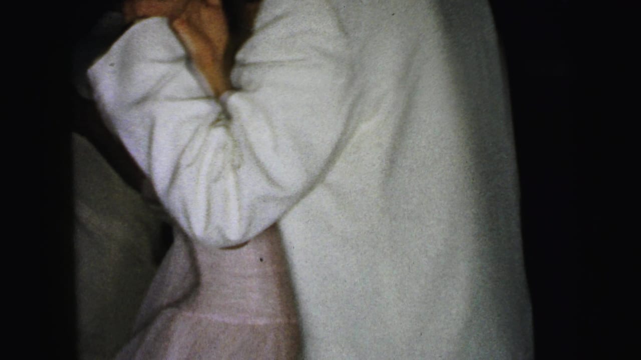 Man and woman dancing very close, cropped at the upper bodies in low light.