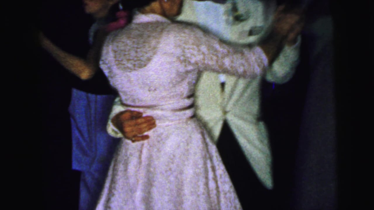 Close view of the same dancing couple, with the woman's lace dress and man's light suit visible.