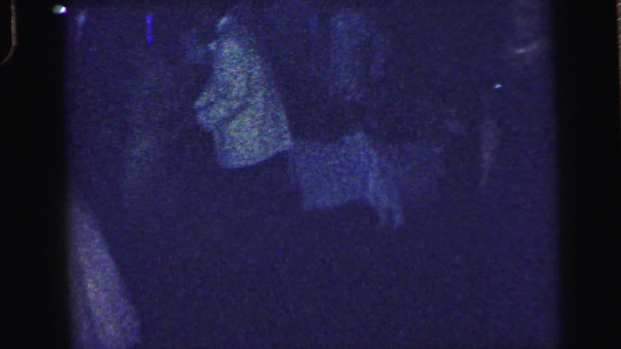 Dark dance floor with a faint figure moving near the center of the frame.